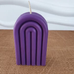 Bougie violette en forme d'arche posée sur un table en bois