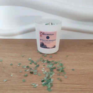 bougie en poot blanc avec étiquette rose incrustée de pierres vertes aventurine posée sur du bois