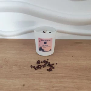 bougie en pot etiquette rose avec pierres grenats sur du bois. fond blanc