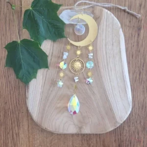 attrape soleil doré pierres de lune et lune sur fond en bois et feuille vertes